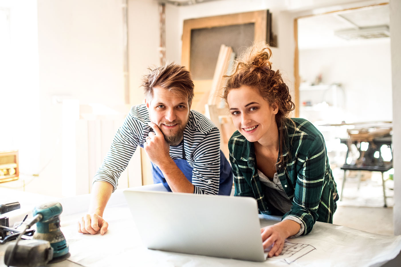 Junges Paar vor Laptop und Bauplänen